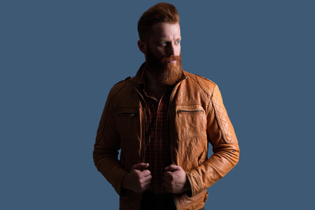 Bearded man isolated on grey. Stylish man with long red beard and moustache. Stylish fashion model. Male casual style. Portrait of guy. Caucasian redhead man in leather jacket.の写真素材