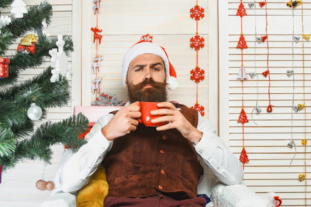 Santa Claus retro man drinking coffee. Happy New Year. Xmas holiday celebration. Santa man in retro style with mug. Delicious cocoa for Christmas. Man celebrate Xmas. Merry Christmas. Cheersの写真素材