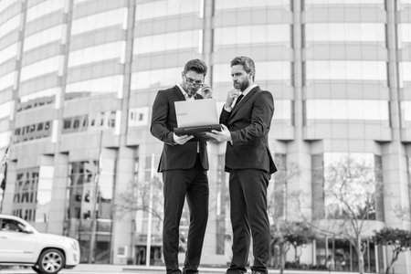 Business online. Men working on laptop. Businessmen working online. Businessmen in suit with laptop. Online working. Businessmen checking email. Business men freelancing outdoor. Business districtの写真素材