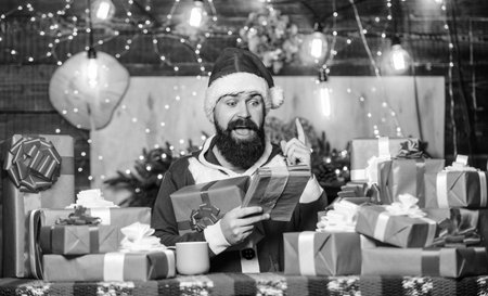 December purchases. Old tradition. Santa Claus routine. Preparing gifts. Buy christmas presents. Man Santa hat preparing for christmas holiday. Merry christmas concept. Winter carnival. Shopping listの写真素材