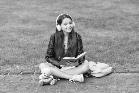 Back to school. Education and knowledge. Girl listen audiobook and read book. Audiobook vs book. Student girl. School education. School girl read book and listen audiobook outdoor. Reading homeworkの写真素材