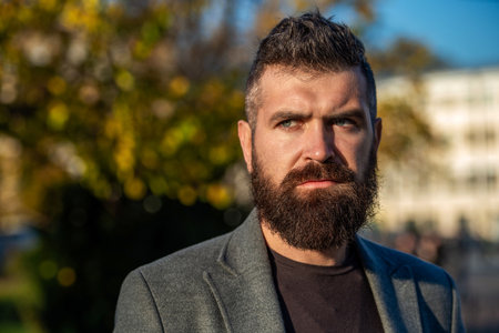 Bearded businessman outdoor. Bearded man having long beard. Businessman in sunset light. City sunset with business man. Man style fashion. Stylish man in casual business styleの写真素材