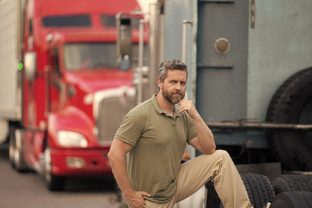 Handsome man driver in front of truck. Trucking owner. Truck driver. Man trucker driver near lorry...