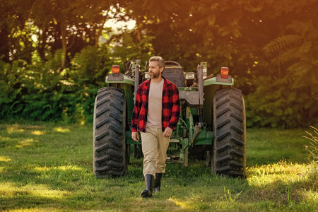 Mature man at tractor. Tractor driver. Agriculture and field work. Farmer in field wearing gum boot with tractor outdoor. Crop harvesting. Agriculture agrotechnology. Farmer with harvesting machineryの写真素材