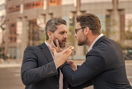 Fight aggression. Angry businessmen. Business conflict. Two businessmen conflicting at fight outdoor. Businessmen having conflict in business. Conflict between boss and employee. Aggressive disputingの写真素材
