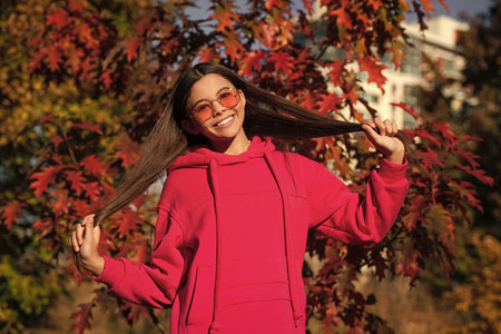 Teenager girl in the autumn park. Fall concept. Girl in autumn style outdoor. Fall style fashion. Autumn leaves and happy young girl in forest. The color and mood of autumn. Funny memoriesの写真素材