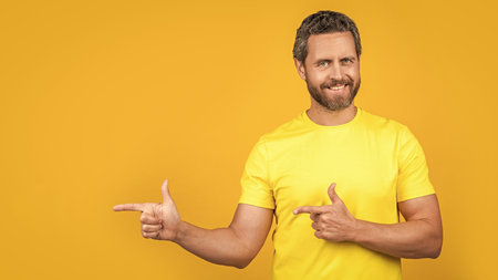 man presenting advertisement isolated on yellow, copy space. man presenting advertisementの写真素材