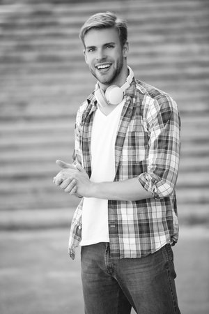 Music lover lifestyle. Millennial man in music headphones outdoor. Modern lifestyle. Student life. Student man has music in headphones. Man millennial generation listen audio. Functional fashionの写真素材
