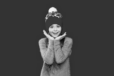 Teen girl in earflap hat of winter fashion style and knitted warm sweater isolated on redの写真素材