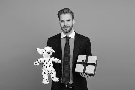 Corporate present. Mens day. Successful boss share gift box. Businessman prepare for romance date. Business reward. Business man with corporate gift box isolated on grey. Commercial gestureの写真素材