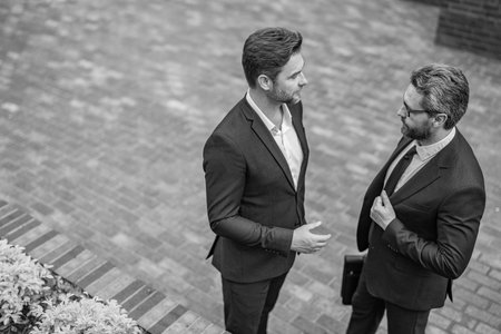 Business partner outdoor. Two businessmen in suit. Business conversation. Project partner talking. Successful businessmen. Copy space. Successful partnership communication. Business successの写真素材