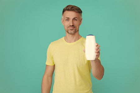 Haircare and skincare. Aftershave cosmetics product. Anti-dandruff hair gel. Offer aftershave. Presenting cosmetics product for men. Man hold aftershave. Man unbranded product. Wash and conditionの写真素材