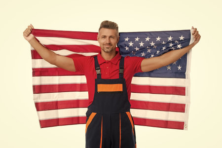 Labor day. Patriotic man with American flag isolated on white. Independence day of America. 4th of July. American flag and man worker. Flag of USA. Independence day. Happy man in worker uniformの写真素材