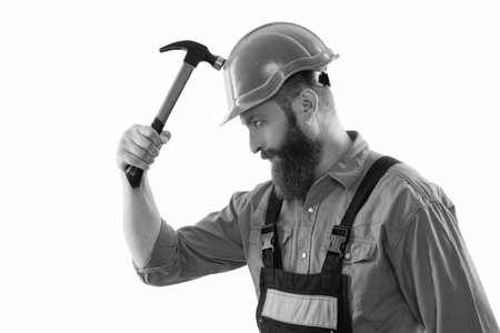Workman repairing with hammer isolated on white. Repair man work. Surface repair. Carpentry and repairing. Repairman in uniform has hammer. Bearded repairman with hammer. Tools for the jobの写真素材