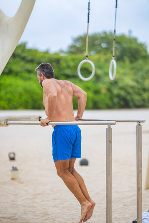 Muscular man with strong back muscles do pushup sport training at outdoor gym. Sportsman pushup in...