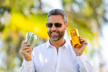 Golden bar. Golden bar and money. Rich businessman hold gold and cash money. Financial success....