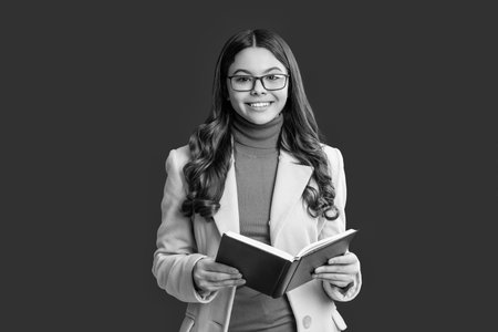 Teen school girl in glasses reading book for knowledge and education in wearing autumn coat on...