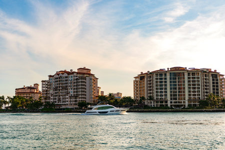 Motor boat yacht floating to marina. Luxury yacht boat at Fisher island. Summer vacation. Fisher island residential building and luxury yacht boat. Panorama view of Fisher island, Miamiの写真素材