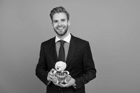 Businessman prepare for romance date. Secret valentine at business corporate. Business man with corporate gift isolated on grey. Corporate present. Mens day. Successful boss hold gift toyの写真素材