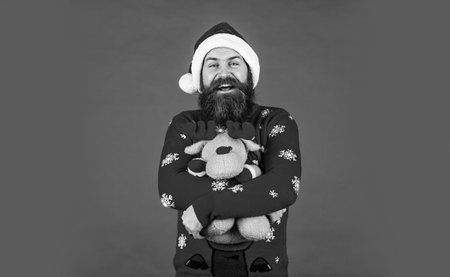 bearded santa claus in hat. celebrate the party. mature man in sweater red background. Christmas party timeの写真素材
