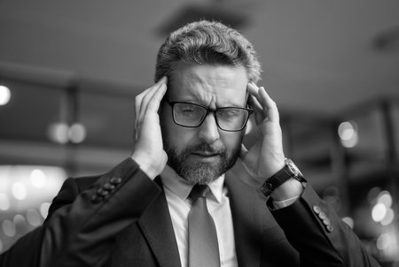 Businessman has headache. Business man suffering from migraine. Business leader after hardworking. Business man in glasses. Man concentrated on success. Serious and concentratedの写真素材