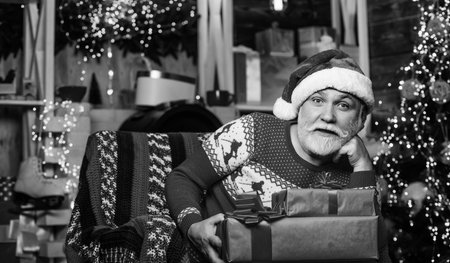 After shopping. happy man with beard. xmas decoration. stack gifts under Christmas tree. winter holiday shopping. party celebration. presents from santa with love. happy new year at homeの写真素材