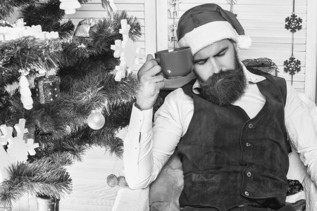 Santa Claus retro man sleeping with coffee mug. Happy New 2025 Year. Xmas holiday celebration. Santa man in retro style with mug. Delicious cocoa for Christmas. Man celebrate Xmas. Merry Christmasの写真素材