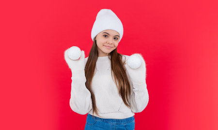 smiling teen girl in warm winter knitted hat and mittens in studio. teen winter girl isolated on redの写真素材