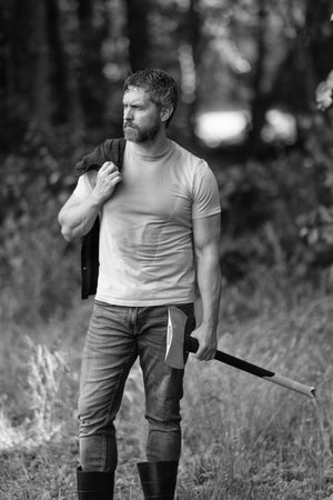 Lumberjack in shirt with heavy axe. Man. Masculinity. Sweating lumberjack man with axe. Lumberjack axe. Strong man work with axe. Lumberjack in woods with an ax.の写真素材