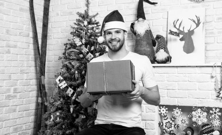 happy young man in santa hat with new year present box. man with red new year present in studio.の写真素材