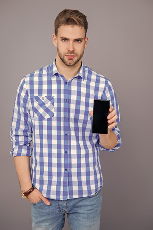 Presenting product. Advertisement of business app. Millennial business man presenting phone screen. Businessman man showing phone isolated on grey. Man showing new business phone appの写真素材