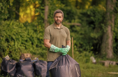 Save environment. Environment plastic pollution. Volunteer man collecting garbage in forest. Environmental protection. Man environmental activist. Environmental conservation. Plastic waste problemの写真素材