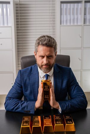 Business success man with gold bar. Investment in precious metal. Golden bullion. Golden bar. Rich businessman hold gold bullion. Financial success. Successful rich man with goldの写真素材