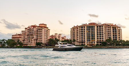 Yacht go to marina. Boating and yachting. Luxury lifestyle. Yacht at Fisher island luxury residential building. Vacation on summer. Fisher island building. Luxury motor boat yacht. Touristic spotの写真素材