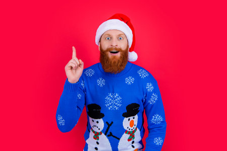 Surprised Santa got Christmas idea. Bearded man in Santa hat keeping finger upの写真素材