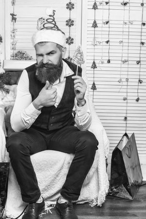 New Year holiday. Man with moustache hold Xmas wreath. Happy New Year. Christmas wreath decoration. Xmas decoration for home. Christmas man show thumb up. Bearded Santa. Bearded man at Christmasの写真素材