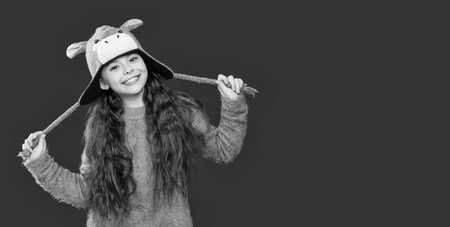 Teenager knitted fashion. Outdoor lifestyle fashion. Teenager girl in a winter warm hat isolated on red. Happy girl in winter hat. Winter fashion style. Happy with joyの写真素材