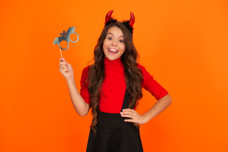 Girl devil in Halloween costume isolated on orange. Trick or treat. All Hallows costume party celebration. All Hallows devil. Imp horns. Girl in Halloween imp costume. Happy Halloween. Horned figureの写真素材