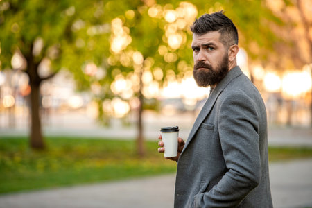 Man drinking morning coffee. Coffee break. Everyday style routine. Bearded man having coffee in autumn city. Fall man in park with coffee cup. Business lifestyle, break time. Copy spaceの写真素材