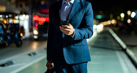 Businessman chatting on phone in night street. Businessman using smartphone. Successful businessman chatting online. Businessman cropped view at night city. Business man chat on cellphone outdoorの写真素材