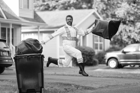 Picking up garbage plastic for cleaning. Keeping garbage plastic in bag for trash. Pollution and recycling. Man jumping and putting garbage bag in trash bin. Environmental protection. Recycle plasticの写真素材