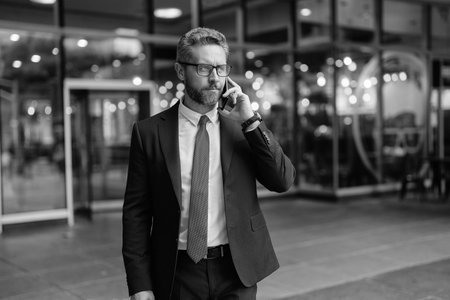 Serious Hispanic business man has phone conversation. Business call. Man in suit talk on phone. Phone call. Mobile communication. Communication. Businessman speak on smartphone outdoorの写真素材