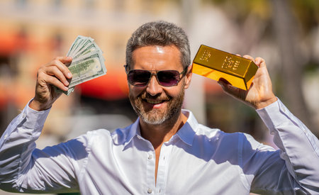 Golden bar and money. Rich businessman hold gold and cash money. Financial success. Successful rich man with gold and money. Business success man with gold bar. Golden bar. Good choiceの写真素材