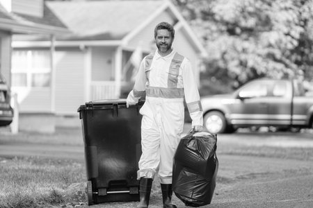 Picking up garbage plastic for cleaning. Keeping garbage plastic into bag for trash. Pollution and recycling. Man putting garbage bag in a trash bin. Environmental protection. Labor dayの写真素材