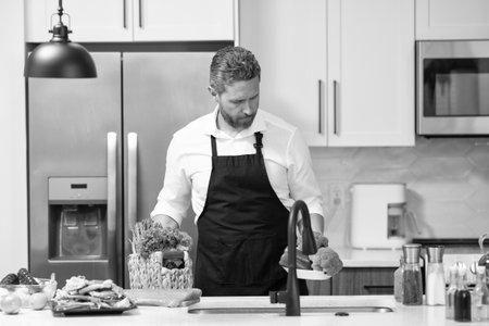 Man cook food in modern kitchen. Cooking healthy salad. Chef cooking in apron. Man cook cooking at kitchen. Chef cook man preparing food. Embrace the joy of cookingの写真素材