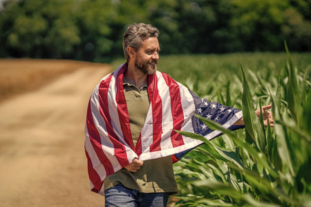 Flag of USA. Independence day. Man in field. Patriotic man with American flag in field. Independence day of America. 4th of July. American flag and man farmer, harvest.の写真素材