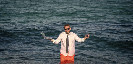 Business man feel confused in sea with laptop. Travel and business. Man freelance worker online. Businessman in summer sea. Online freelance work. Businessman office worker with laptopの写真素材
