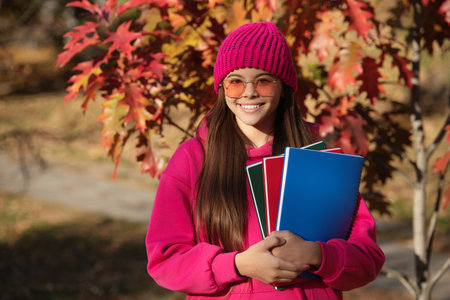 teen girl in autumn park outdoor. autumn is time to study. education and knowledge. school education. back to school. autumn girl holding school homework. education for college student. copy spaceの写真素材