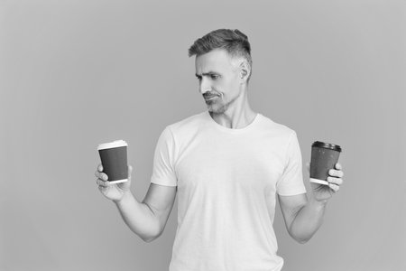 Man drinking coffee. Warm morning relax. Coffee break with barista man. Mature man choose decaf coffee cup isolated on blue. Morning coffee time. Lifestyle concept. Drinking decaf. Takeaway paper cupの写真素材