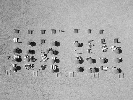 Sea relax under beach umbrella. Travel to sea. Aerial top view of sand exotic beach with sunbed and umbrella. People on beach enjoying sun. Summer vacation. Beach vacation at sea in summerの写真素材